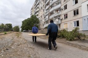 Men carry plywood near a house damaged by Russian shelling in Kupyansk