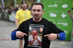 A participant in a charity run shows a photograph of a fallen soldier on a T-shirt