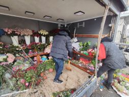 Workers at a flower shop clean up trash and broken glass after a part of a downed drone fell into a shop in Kyiv