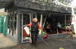Workers at a flower shop clean up trash and broken glass after a part of a downed drone fell into a shop in Kyiv