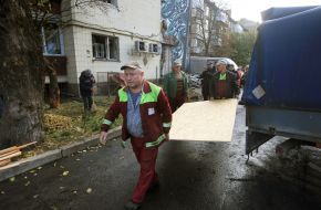 Utility workers carry plywood to board up windows in a house in Kyiv that were broken due to falling debris from downed drones