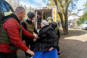 An elderly woman on a stretcher is carried into the cabin of an ambulance during an evacuation in the city of Kupyansk