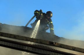 A rescuer extinguishes a fire on a roof after a drone wreckage fell in the Solomianskyi district of Kyiv