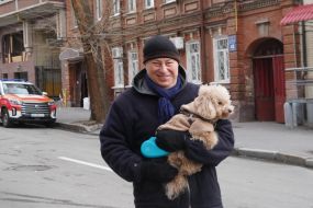 A man with a dog in his arms on the street in Kharkiv