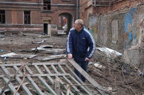 Чоловік біля зруйнованого після ракетного удару забору у Харкові
