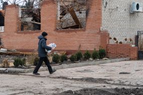 A man walks near destroyed houses in the village of Borovaya, Kharkiv region