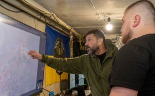 Servicemen of the 57th mortar brigade near a map in the Kharkiv region