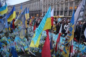 Participants of the Christmas procession pass by the makeshift memorial "Lawn of National Memory" in Kyiv