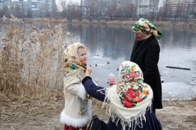 Женщины и девочка в традиционных украинских платках стоят на берегу Иорданского озера в Киеве