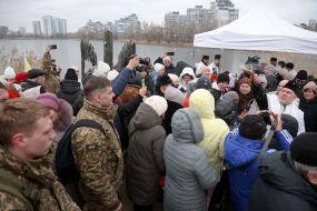 A priest sprinkles holy water on parishioners on the shore of Lake Jordan in Kyiv