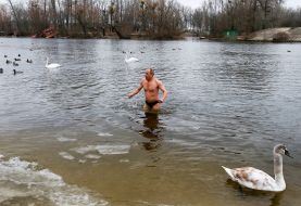 A man dives into the water in the swan lake at the Hydropark