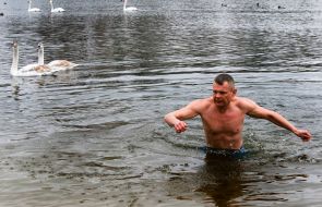 A man dives into the water in the swan lake at the Hydropark