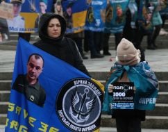 Жінка та дитина з військовим прапором та плакатом на Майдані Незалежності в Києві