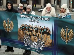 Женщины держат баннер с фотографией военнослужащих и надписью "Оркестр морской пехоты" на Майдане Незалежности в Киеве.