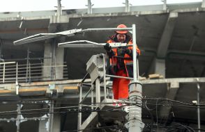 An electrician repairs a streetlight after being hit by ballistics near the Lukyanivska metro station in the central district of Kyiv