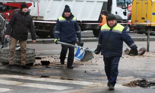 Utility workers carry a damaged road sign