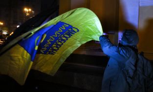 A man holds a flag with the inscription "Self-defense of the Maidan"
