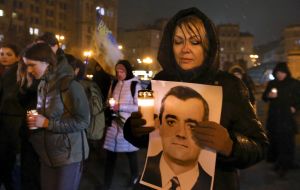 A woman holds a lit lamp and a portrait of one of the fallen Heroes of the Heavenly Hundred