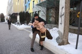 A man pushes a topless FEMEN activist near the German Embassy in Kyiv