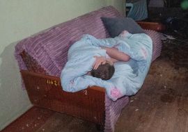 A patient in a blanket on a couch awaits evacuation after a drone strike on a hospital in Kharkiv