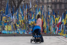 Woman with a baby stroller near the makeshift memorial "Lawn of National Memory" in Kyiv