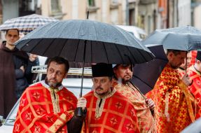 Clergymen stand under umbrellas