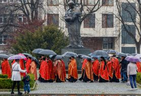 Clergymen under umbrellas walk near the monument to Taras Shevchenko in Uzhhorod