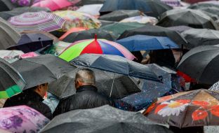 Believers walk under umbrellas through the streets of Uzhhorod