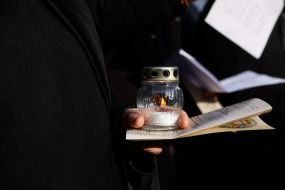 Зажженная лампадка в руках у участника Крестного пути