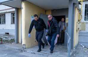 Men carry the body of a deceased person out of a house after a ballistic missile attack with cluster munitions on Kharkiv