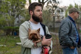 Мужчина держит собаку на руках после удара баллистическими ракетами с кассетной начинкой по Харькову