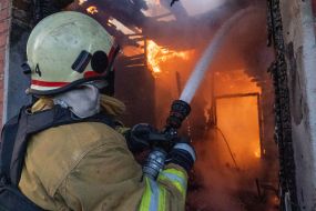 A rescuer puts out a fire in a house after a ballistic missile attack with cluster munitions on Kharkiv