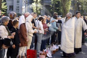 Священник окропляет святой водой верующих