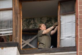 Woman near broken window on balcony after a massive Russian attack with mortars and missiles on Kharkiv