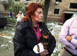 A woman with a bloodied face holds a dog in her arms after a massive Russian attack on Kyiv