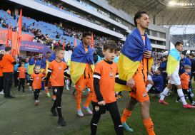 Football players enter the field accompanied by children