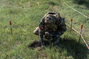 A policeman from the explosives disposal unit of the National Police of Ukraine prepares a discovered TM-62 anti-tank mine for removal