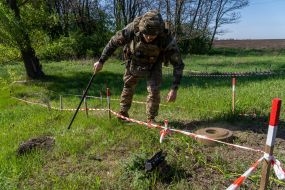 A police officer from the explosives disposal unit of the National Police of Ukraine stands next to a removed TM-62 anti-tank mine