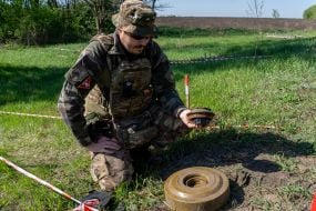 A police officer from the explosives disposal unit of the National Police of Ukraine next to a removed TM-62 anti-tank mine