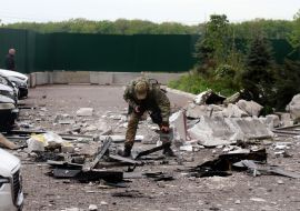 A military explosives technician examines the wreckage of a drone