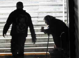 An elderly woman begs for alms in an underpass
