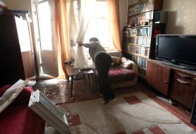 A woman removes glass from a broken window in an apartment after a Russian drone "Geran-2" hit a residential building in the Obolonskyi district of Kyiv