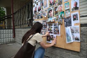 A woman hangs photos of missing people on a stand