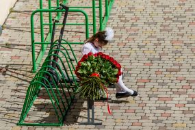 Школьница сидит возле большого букета из роз