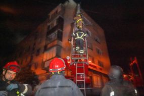 Rescuers climb a ladder to the upper floors of a residential building damaged after a drone attack in Kharkiv