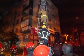 Rescuers climb a ladder to the upper floors of a residential building damaged after a drone attack in Kharkiv