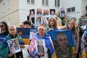 People hold photos of missing people