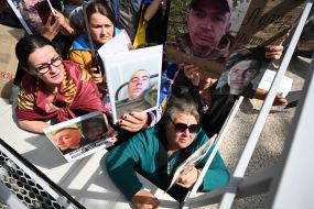 People hold photos of missing people