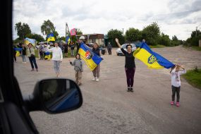 People along the road meet buses with prisoners of war