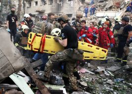 Providing assistance to a State Emergency Service employee near a residential building destroyed as a result of a direct missile hit in the Solomianskyi district of Kyiv